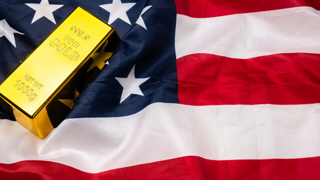 Gold bar lies on top of a rippled United States of American flag.
Gold serves as a primary safe-haven asset for investors during economic uncertainty.