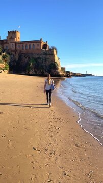 Woman tourist walking on sandy beach near castle in ferragudo portugal- Algarve tourism