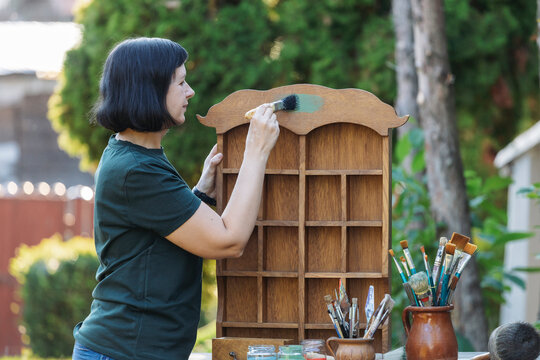Mid woman painting furniture outdoors at home, relocation and diy concept.