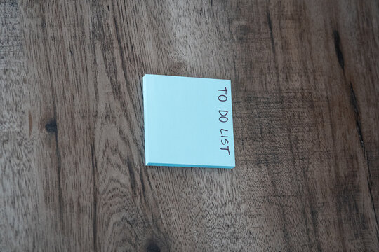 Blue sticky note pad with to do list text on dark wooden desk with copy space