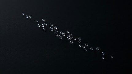 Obraz premium Scattered small clear droplets forming a diagonal line on a black background, keywords: scattered