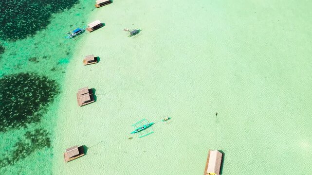 A floating native cottage on a sandbar in the tourist island of Caramoan in the Philippines. Summer and travel vacation concept. A lagoon with floating crotches, top view.