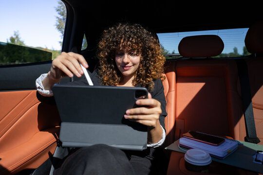 Businesswoman working remotely on tablet inside car