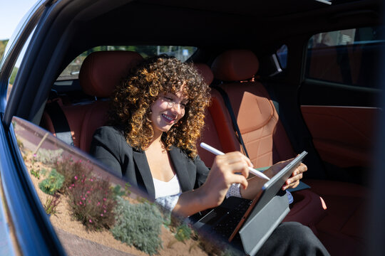 Businesswoman working on tablet inside car with leather seats