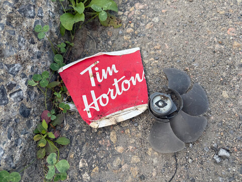 Une tasse de caf&eacute; Tim Hortons froiss&eacute;e sur une route asphalt&eacute;e de la ville	