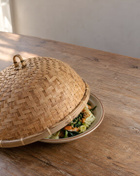 Woven Bamboo Food Cover Lifted to Reveal Saut&eacute;ed Vegetables