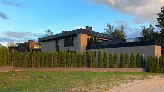 Green fence at mansory suburb house features unique desig. Villa with fence from thuja. Luxury suburb house. Luxury Modern house. Fence made of arborvita. Modern house with green landscape.