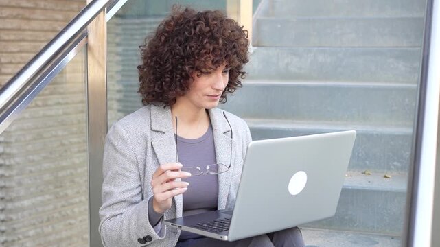 A Focused Professional Engaged in Work on a Laptop in a Trendy Modern Outdoor Setting