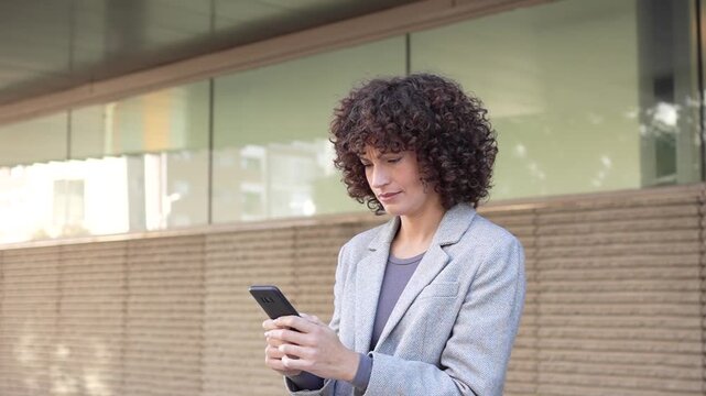 A businesswoman uses her smartphone outdoors, showcasing her dynamic approach to communication