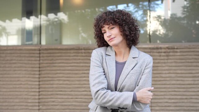 A selfassured individual boasting curly hair poses gracefully outdoors, exuding charm