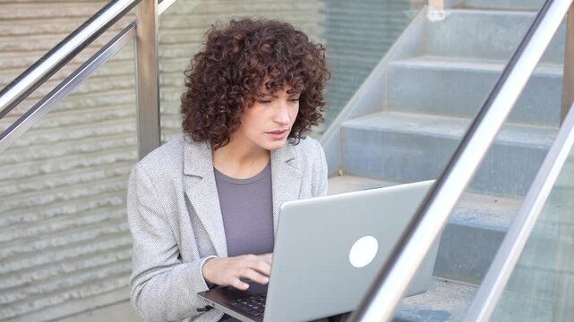 A Professional Woman Engaged in Working on Her Laptop in a Stylish, Modern Office Setting