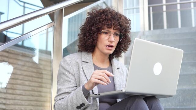 A Professional Woman Engaged in Work on Her Laptop While Seated Outdoors in Nature