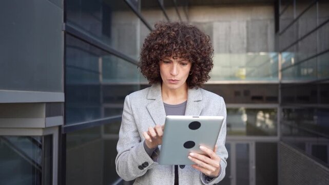 A professional woman is utilizing a tablet in an impressive modern architectural setting