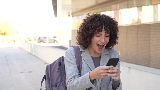 A Professional Woman Engaged with Her Smartphone While Outdoors in a Bustling Environment