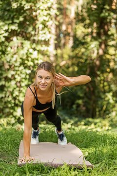 Woman Doing Plank Exercise with Arm Raise Outdoors