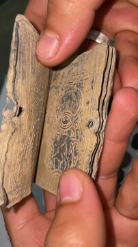 Ancient Hebrew manuscript scroll with antique coins on a dark table, close up footage