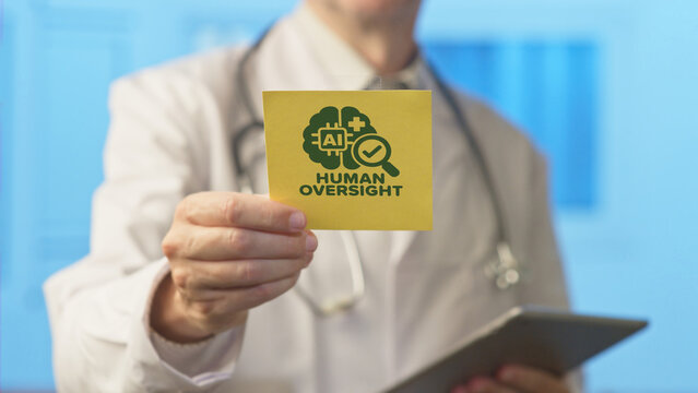 Medical professional holding a sticky note with an artificial intelligence human oversight icon, highlighting the importance of supervision and regulation in modern healthcare technology