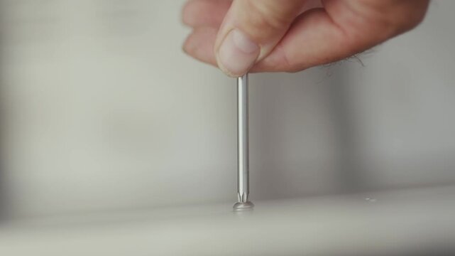 Hand presses stainless steel pin into outdoor kitchen countertop surface