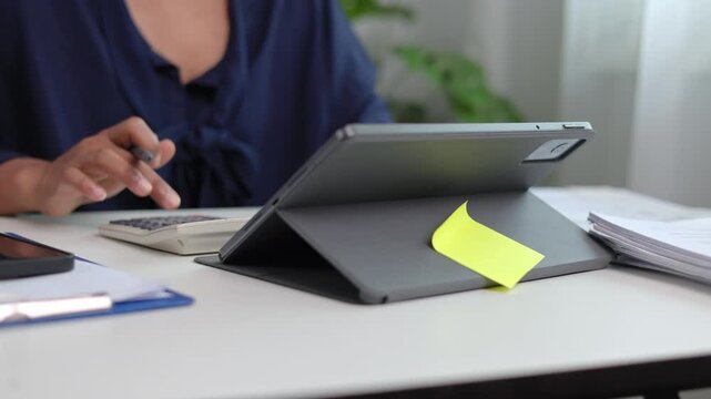 Close perspective of female hands navigating tablet screen with stylus pen while operating digital workflow application at modern office desk during working business hours