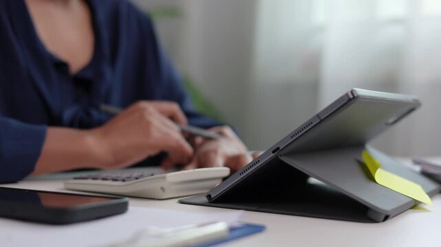 Close up hands of female manager drawing workflow graphics on tablet display using electronic stylus pen near white coffee cup and paperwork folder on office table background