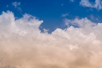 Obraz premium Soft Cumulus Clouds Over Deep Blue Sky With Warm Golden Light and Airy Atmospheric Texture