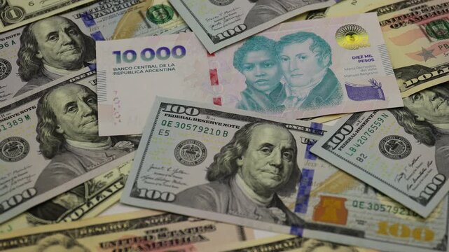 United States dollar and Argentine peso banknotes arranged together as physical paper currencies, displaying the distinctive colors, denominations, portraits, national symbols