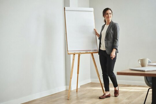 Workshop facilitator standing at ease beside a blank flip chart easel