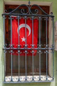 Turkish flag hanging on a decorative metal window grate in an old street of Istanbul