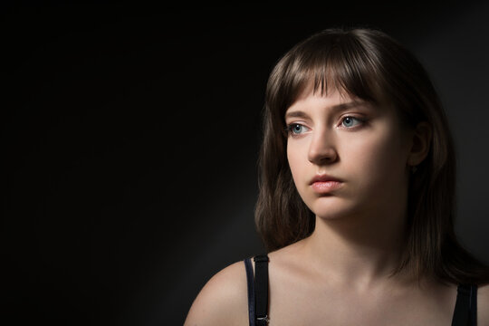 Portrait of a beautiful teenage girl posing against a dark background