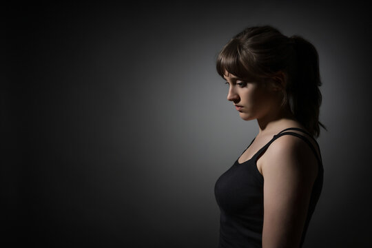 Portrait of a beautiful teenage girl posing in profile against a dark background
