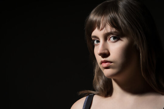 Portrait of a beautiful teenage girl posing against a dark background in beauty style