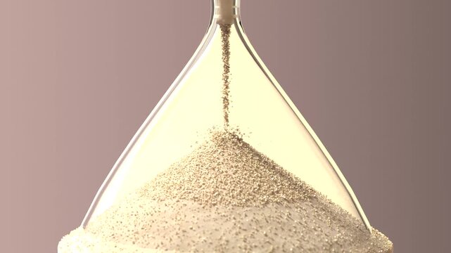 Flowing glass hourglass with gravity pulling sand through throat in studio on base