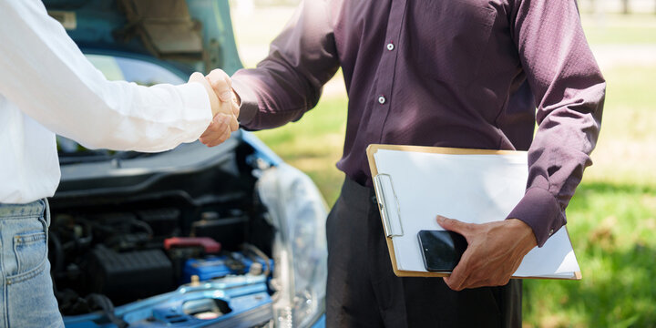 Insurance agent and driver shaking hands after car breakdown inspection