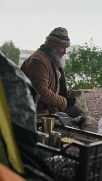 Portrait of senior Caucasian homeless man holding beverage can outdoors. Clip suits poverty awareness documentaries and charity campaigns, vertical