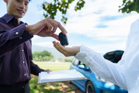 Asian man handing car key to customer for vehicle rental deal