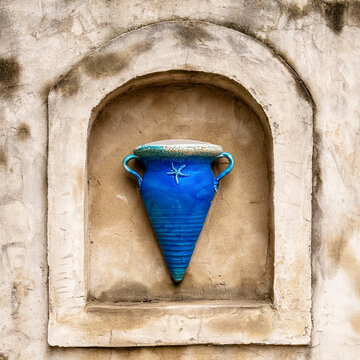 Blaue maritime Vase in einer groben rauen dreckigen Wandnische