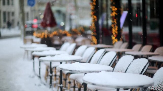 Traditional outdoor cafe chairs and round tables in Paris covered with a fresh layer of snow.
