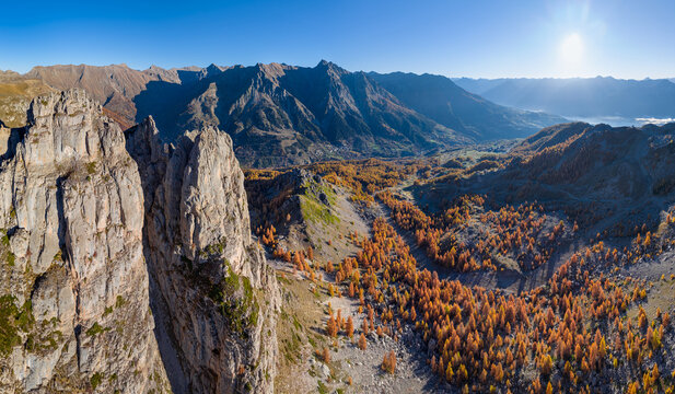 Aerial autumn view of the Aiguilles de Chabrieres and Ecrins National Park mountains, with golden larch forests and the village of Reallon in the Hautes-Alpes, French Alps