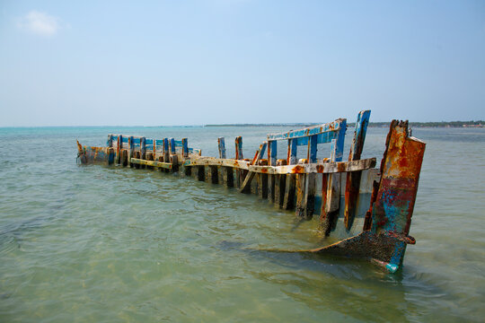 Skeletal remains of an old rusted wooden shipwreck partially submerged in shallow coastal water