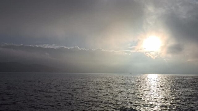 Sun halos and radiant sunburst breaking through clouds over a calm ocean
