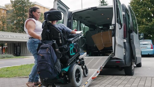 Personal assistant stowing an accessible ramp after a powered wheelchair user exiting an adapted vehicle, inclusive mobility concept.