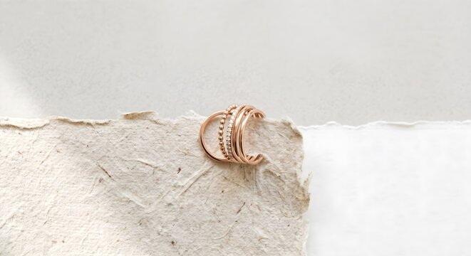 Elegant Minimalist Gold Ring Resting on Textured Handmade Paper Background
