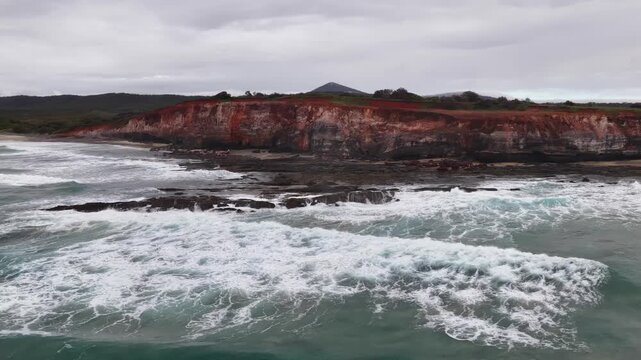 Aerial video flying over the rugged coastline at Lake Arragan, featuring sandy shoreline, rocky formations and waves rolling in from the Pacific Ocean