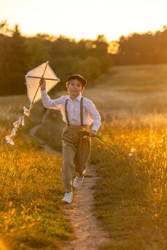 Sweet preteen child, boy, playing in a field on sunset with kite and old vingate car, walking with grandmother in the countryside