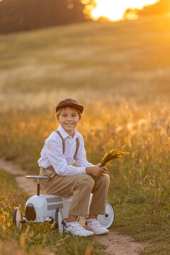 Sweet preteen child, boy, playing in a field on sunset with kite and old vingate car, walking with grandmother in the countryside
