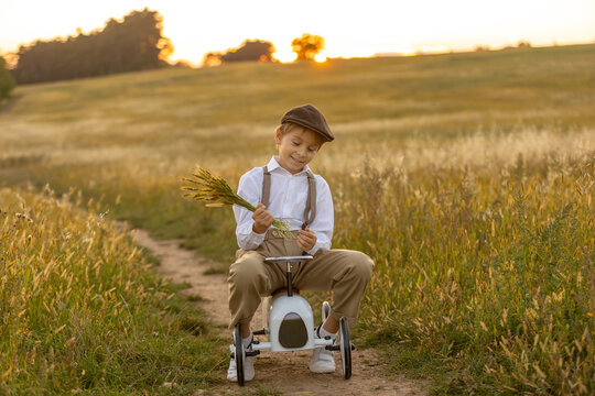 Sweet preteen child, boy, playing in a field on sunset with kite and old vingate car, walking with grandmother in the countryside