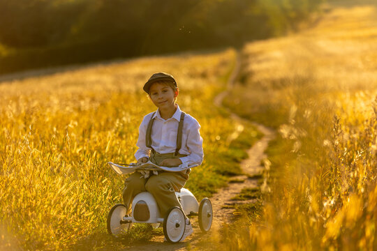 Sweet preteen child, boy, playing in a field on sunset with kite and old vingate car, walking with grandmother in the countryside