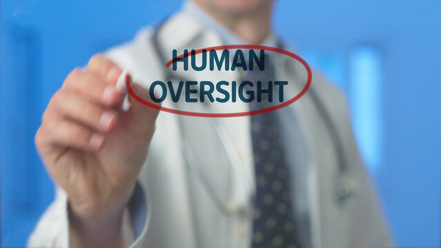 Doctor hand outlining human oversight text on a clear display, emphasizing the critical need for human control and ethical considerations in artificial intelligence and technology development