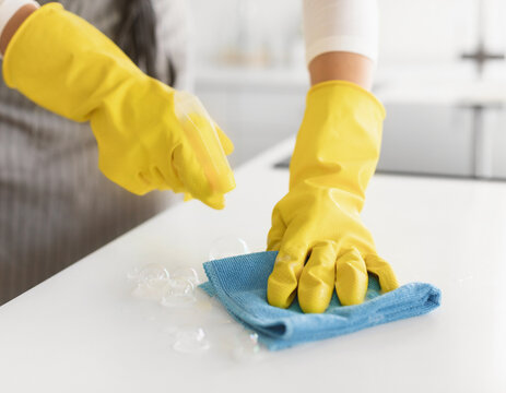 Hands in rubber gloves cleaning kitchen countertop
