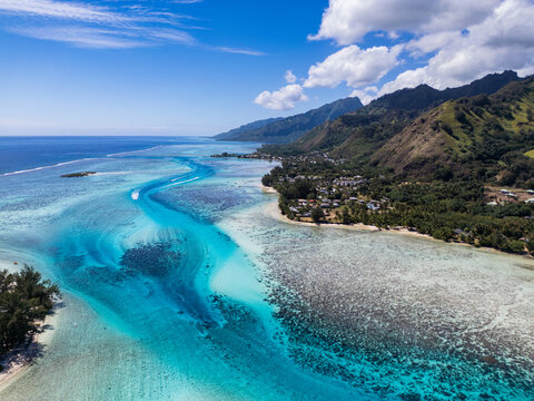Aerial view of the turquoise lagoon and coral reefs surrounding the lush volcanic mountains of Mo'orea in Moorea-Maiao, Windward Islands, French Polynesia.